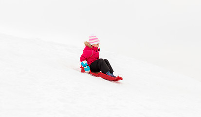 Image showing happy little girl sliding down on sled in winter