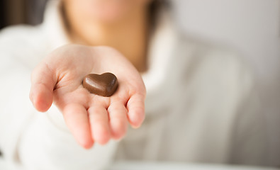 Image showing close up of hand with heart shaped chocolate candy