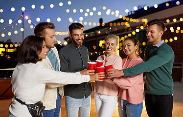 Image showing friends clinking party cups on rooftop at night