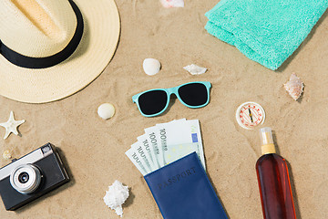 Image showing money in passport, shades and hat on beach sand