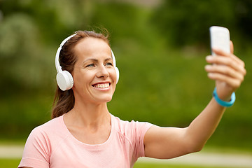 Image showing woman in phones takes selfie by smartphone at park