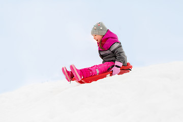 Image showing happy little girl sliding down on sled in winter