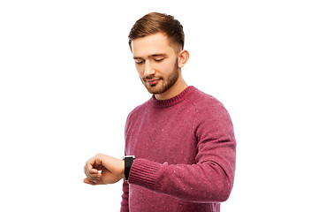 Image showing smiling young man checking time on wristwatch