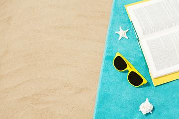 Image showing sunglasses and book on beach towel on sand