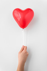 Image showing close up of hand holding red heart shaped balloon