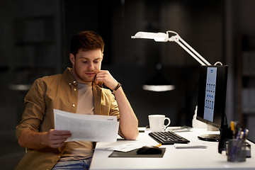 Image showing designer with papers and computer at night office