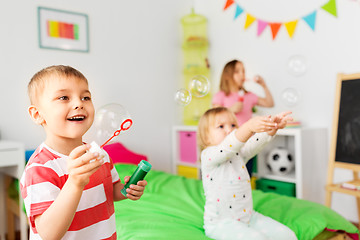 Image showing happy children blowing soap bubbles at home
