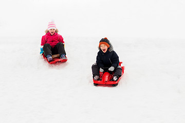 Image showing happy kids sliding on sleds down hill in winter