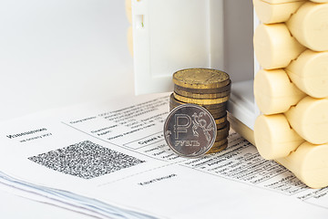 Image showing A stack of money and one ruble coin in the accounts for the apartment, in front of the door to the house