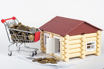 Image showing Trolley with money on the bills for the apartment, next to the toy house