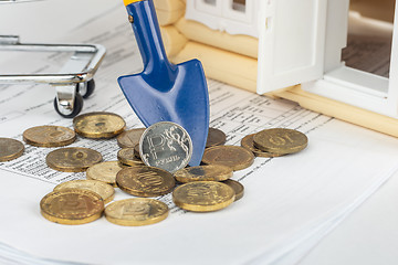 Image showing There is a ruble coin on the shoulder, next to the bills for the apartment and the toy house