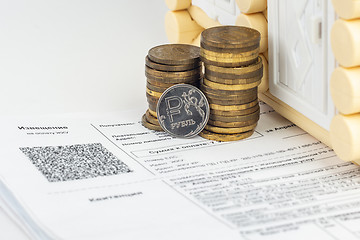 Image showing A stack of money and one ruble coin in the bills for an apartment