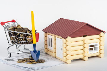 Image showing A trolley with money in the bills for an apartment, a shovel stands next to it, a toy house is near