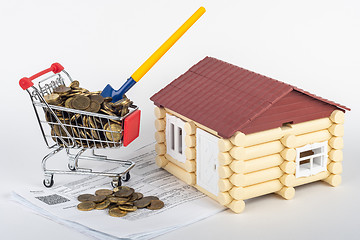 Image showing A trolley with money in the bills for an apartment, a shovel stuck in a trolley, a toy house next to it