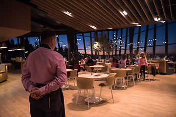 Image showing waiter standing with hands behind his back