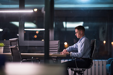 Image showing man working on laptop in dark office