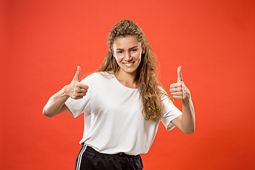 Image showing The happy business woman standing and smiling against red background.