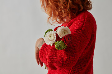 Image showing Young red-haired woman with tender flowers of a Ranunculus on a gray background with copy space. Greeting card layout