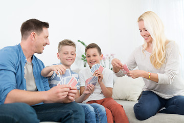 Image showing Happy young family playing card game at home.