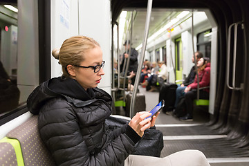 Image showing Young girl reading from mobile phone screen in metro.