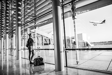 Image showing Young woman waiting at airport, looking through the gate window.