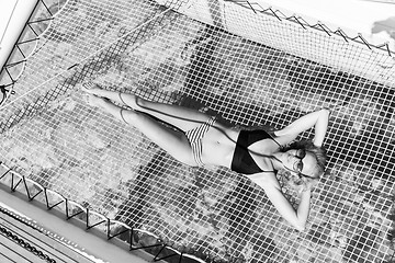 Image showing Womanin bikini tanning and relaxing on a summer sailin cruise, lying in hammock of luxury catamaran boat.