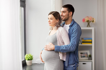 Image showing man hugging pregnant woman at window at home