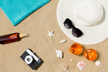 Image showing drinks, hat, camera and sunglasses on beach sand