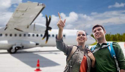 Image showing couple of tourists with backpacks over plane