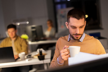 Image showing happy male office worker drinking coffee