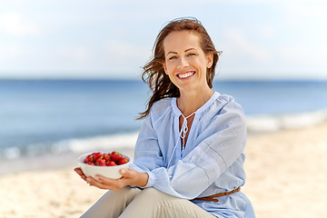 Image showing woman holding bowl with strawberries on beach