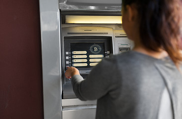 Image showing woman at atm machine with bitcoin icon on screen