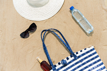 Image showing beach bag, sunscreen, sunglasses and hat on sand