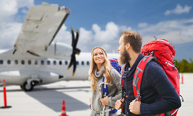 Image showing couple of tourists with backpacks over plane