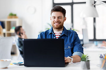 Image showing smiling creative man with laptop working at office