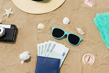 Image showing money in passport, shades and hat on beach sand