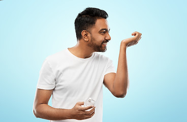 Image showing happy indian man with perfume over blue background