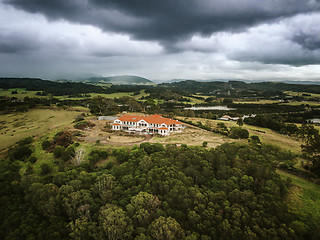 Image showing Storm clouds loom over abandoned mansion in rural setting