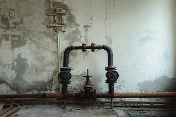 Image showing Old water pipes against abandoned wall