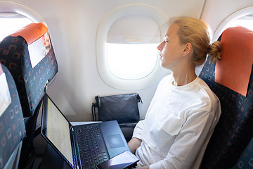 Image showing Tired business woman napping on airplane during her business trip woking tasks.