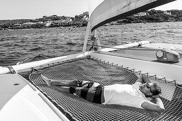 Image showing Sporty man relaxing on a luxury catamaran sailing boat.