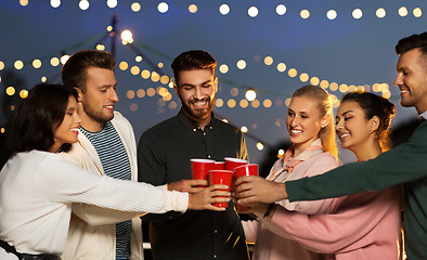 Image showing friends clinking party cups on rooftop at night
