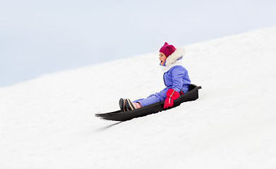 Image showing happy little girl sliding down on sled in winter