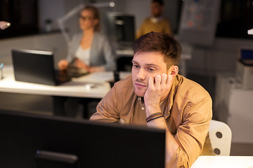 Image showing tired or bored man with computer at night office