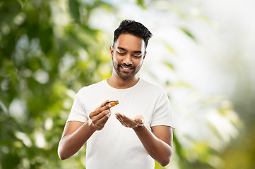 Image showing indian man applying grooming oil to his hand