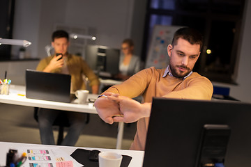 Image showing man working late at night office and stretching