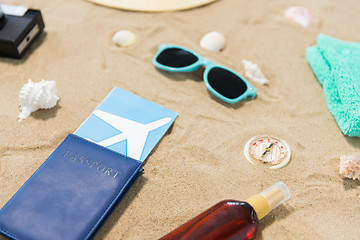 Image showing travel tickets, camera and hat on beach sand