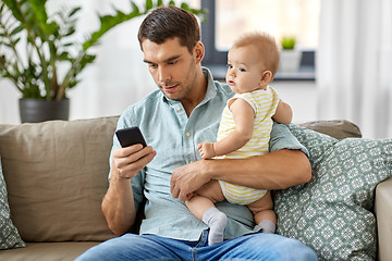 Image showing father with baby daughter using smartphone at home