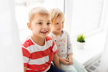 Image showing happy little kids sitting on window sill