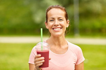 Image showing woman drinking smoothie after exercising in park